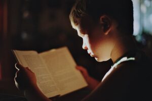 Enfant écoutant une histoire de dragon pour enfant, livre ouvert sur les genoux