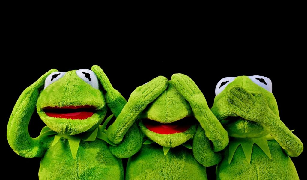 Grande peluche dragon verte posée au pied d'un lit dans une chambre