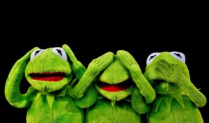 Grande peluche dragon verte posée au pied d'un lit dans une chambre
