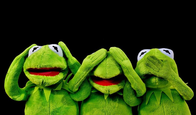 Grande peluche dragon verte posée au pied d'un lit dans une chambre